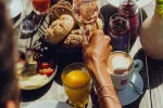 Frühstückstisch mit Lebensmitteln und Getränken, Hand greift nach Essen