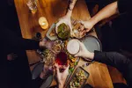 Hände stoßen Getränke über einem Tisch mit Essen an
