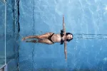 Frau schwimmt entspannt in einem klaren Pool.