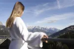 Person in Bademantel mit Blick auf Berge und Tal