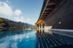 Blick auf Swimmingpool mit Holzdecks und Bergen im Hintergrund