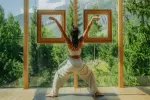 Person übt Yoga in einem holzrahmten Raum im Freien