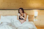 Frau im Bett mit einem Handy in der Hand