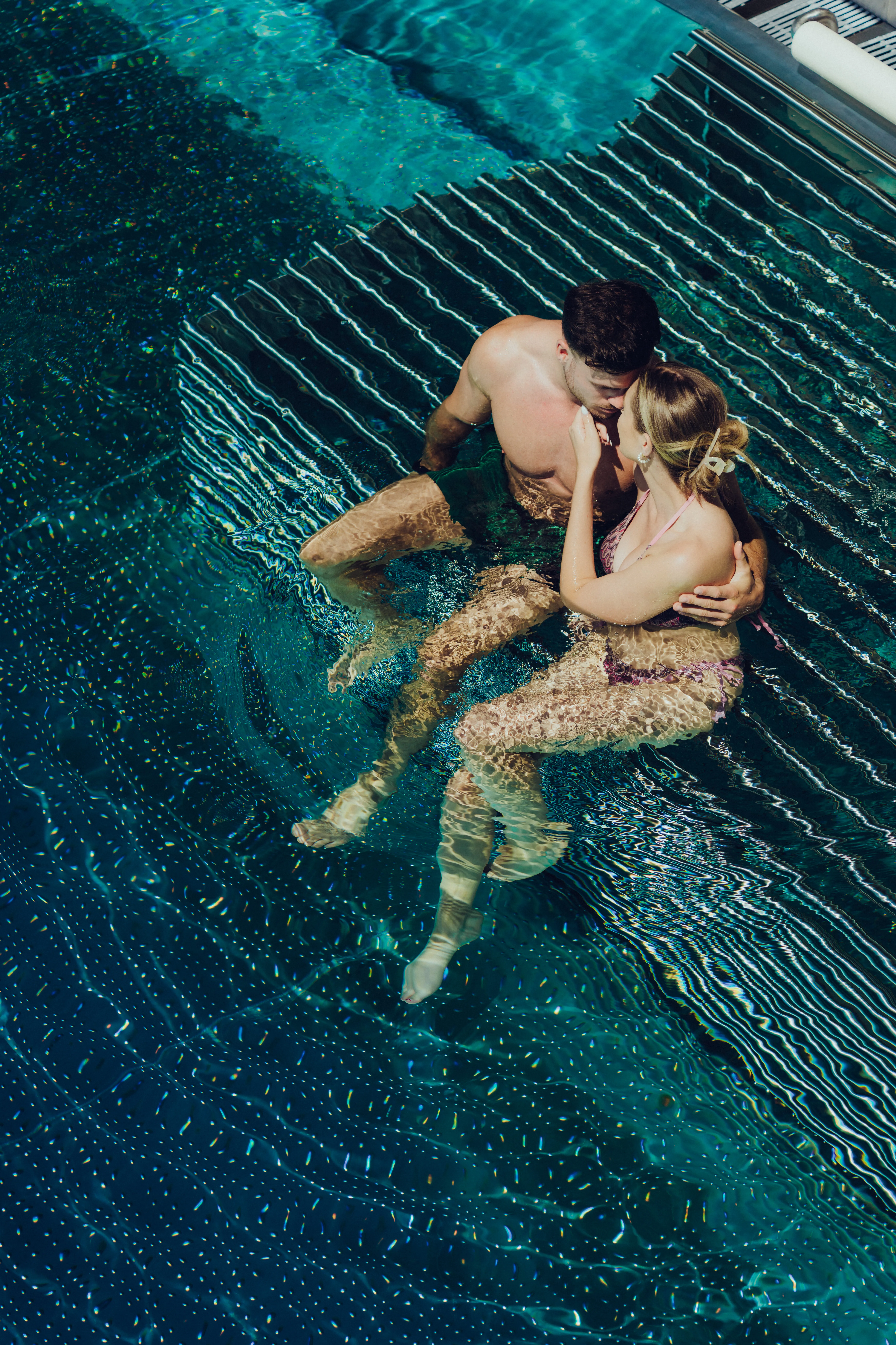 Paar sitzt im Wasser eines Pools und schaut sich an