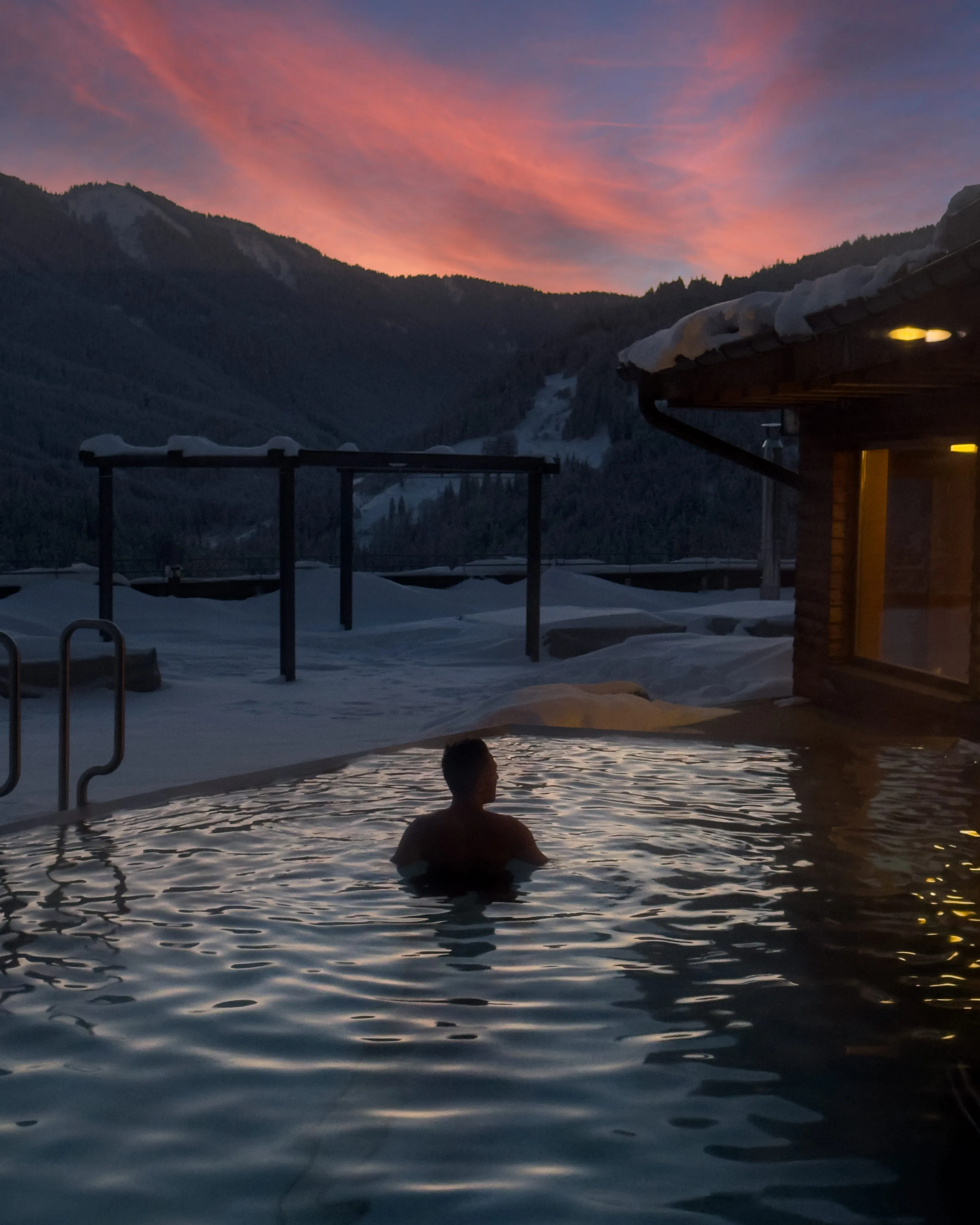 Person im Außenpool mit Bergblick und Sonnenuntergang