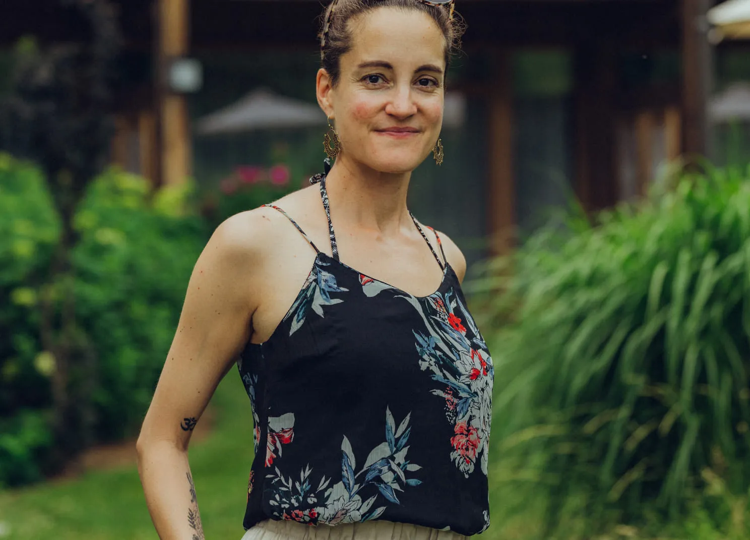 Person in einem Garten, trägt ein blumiges Oberteil