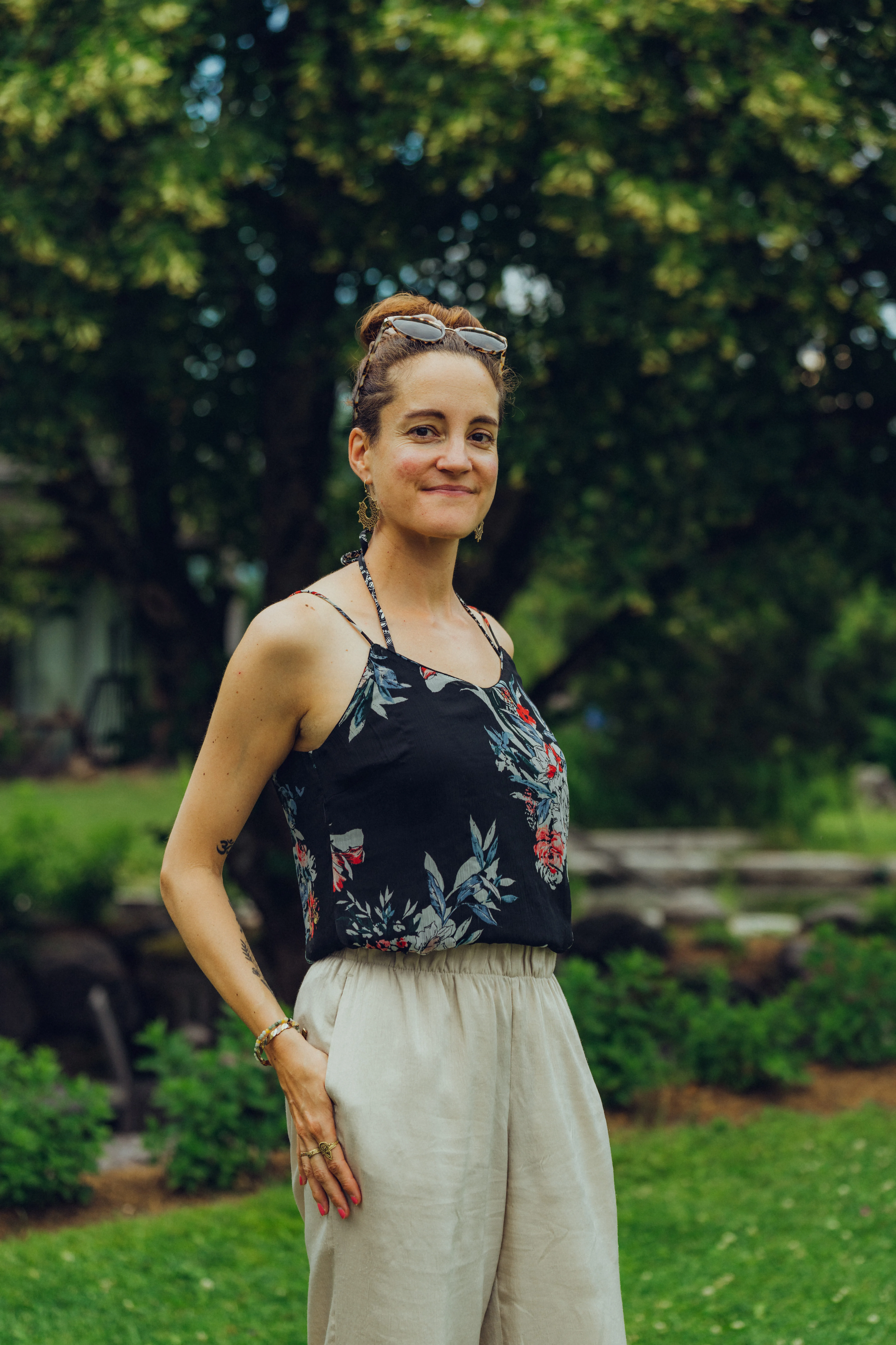 Frau in Blumenoberteil und beigen Hosen im Garten