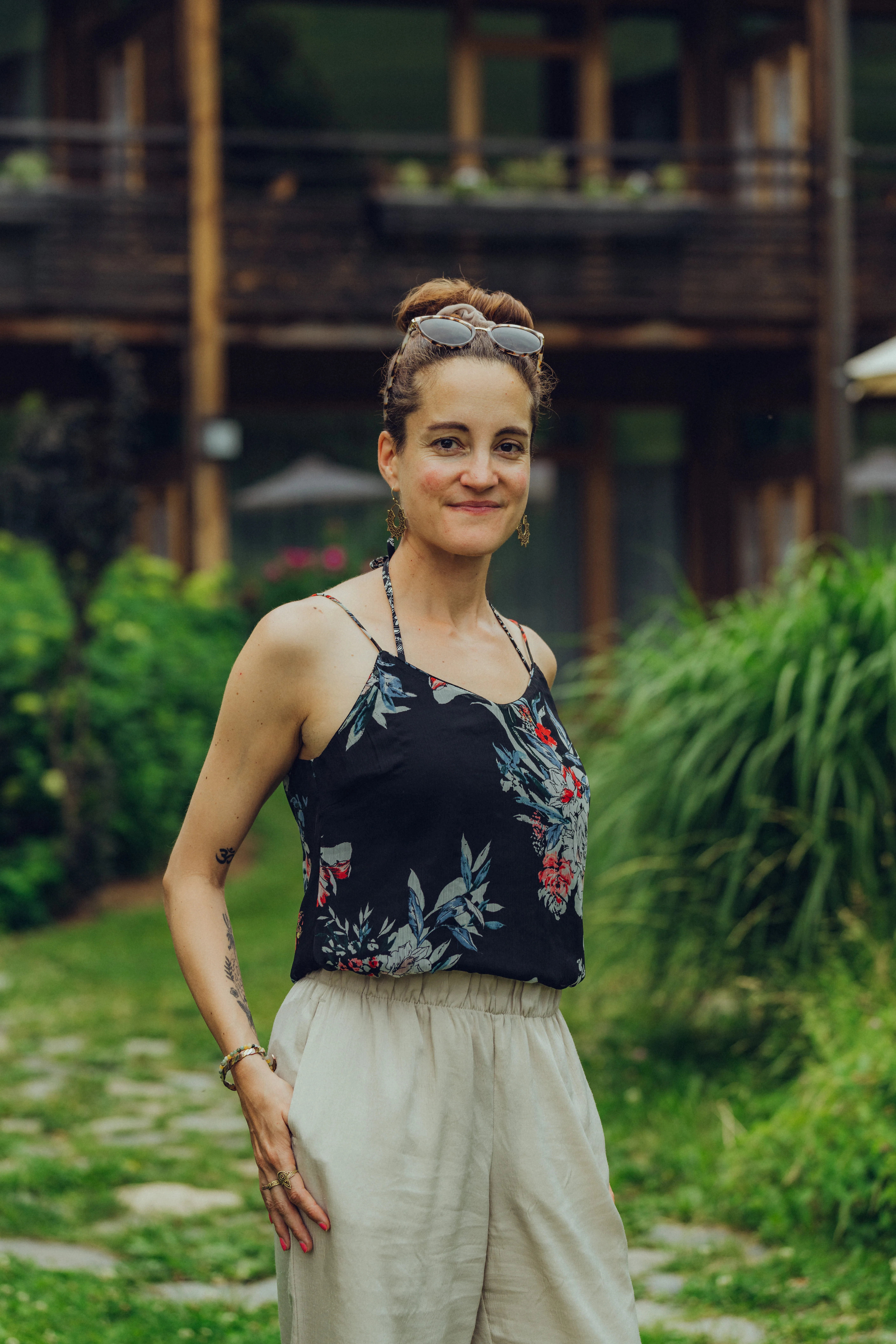 Person in Blumenoberteil und hellen Hosen in einem Garten